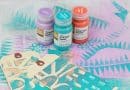 Acrylic paint pots surrounded by mixed media artwork.