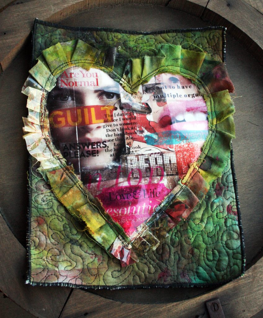 Small art quilt featuring a large heart made up of magazine image and surrounded by a ruffle.