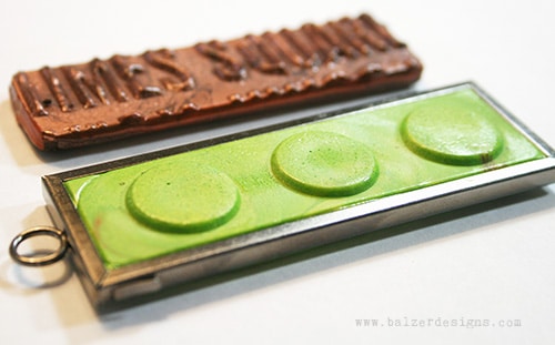 An angled view of a green UTEE pendant with three dots and a text pedant blurry in the background.